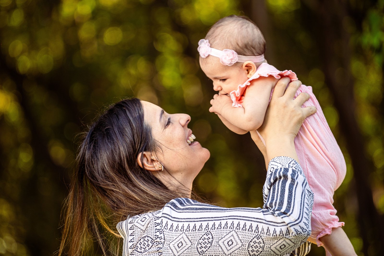 Mother lifting her baby joyfully outdoors