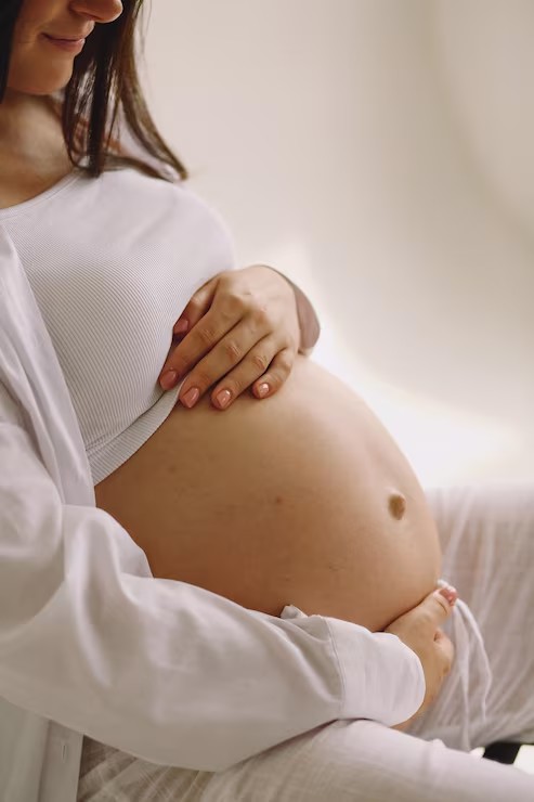 Pregnant woman gently holding her belly at home